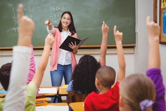 copii in sala de clasa cu mainile ridicate
